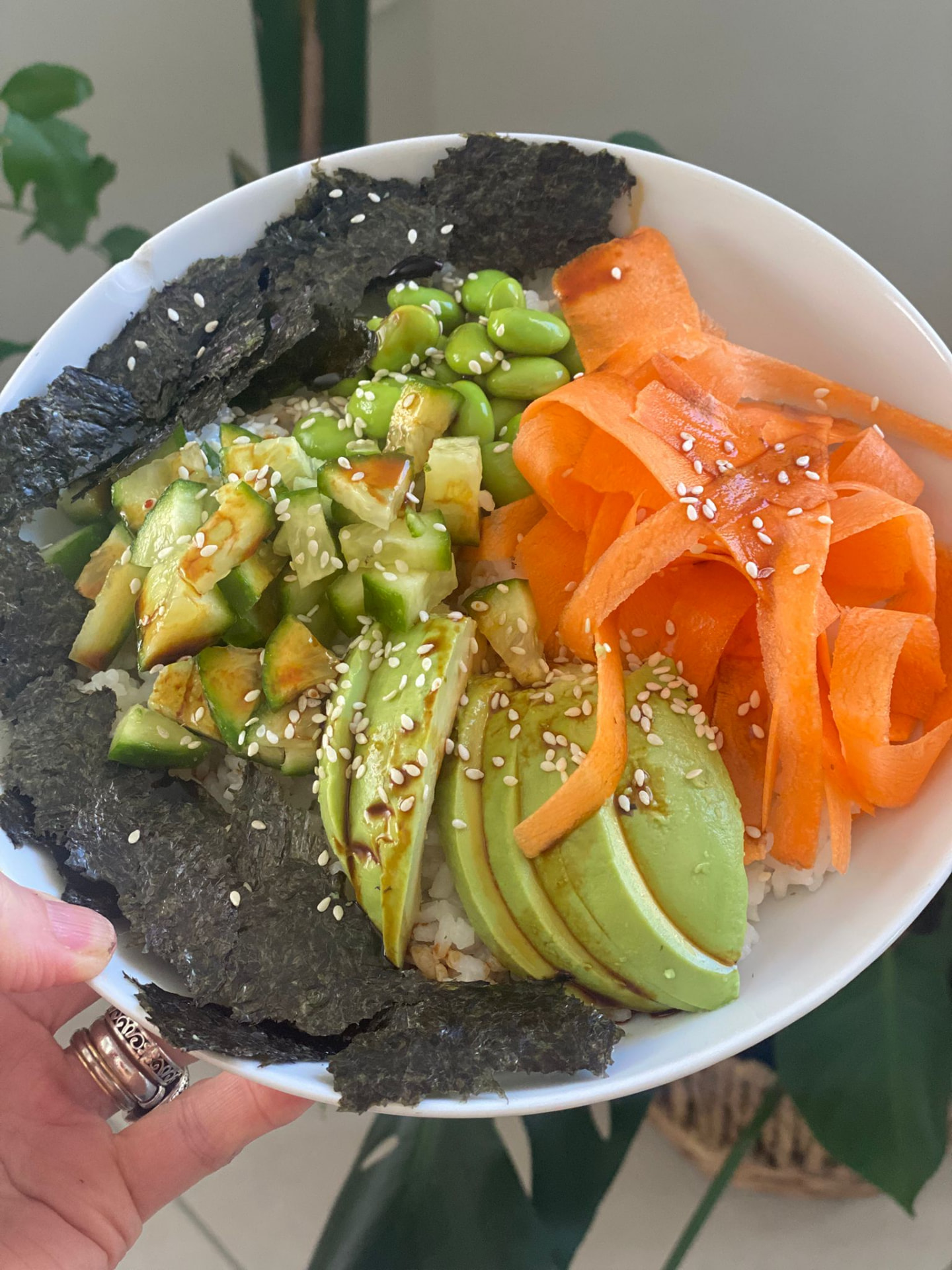 A colourful poke style bowl with rice, edamame, avocado, carrot and nori