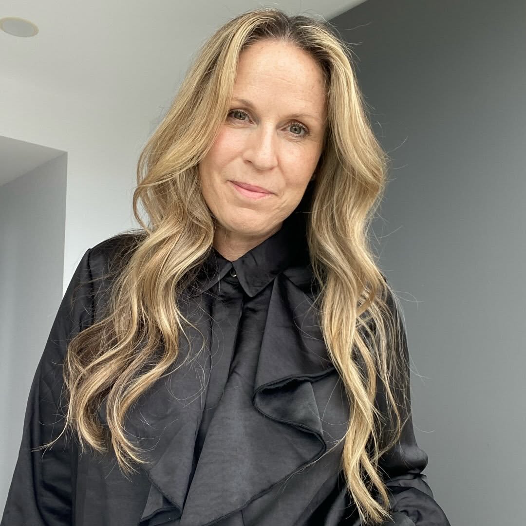 Ali Villani with long blonde hair wearing a black blouse